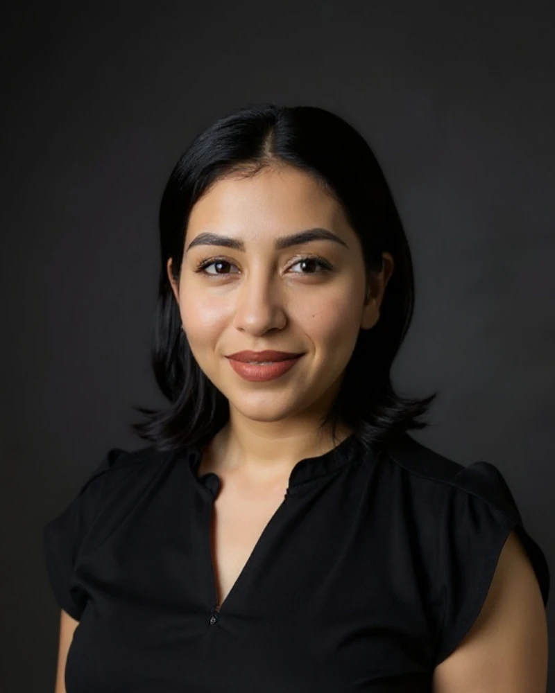 Portrait of Fatima, a therapist with shoulder-length dark hair, smiling outdoors in soft natural light.